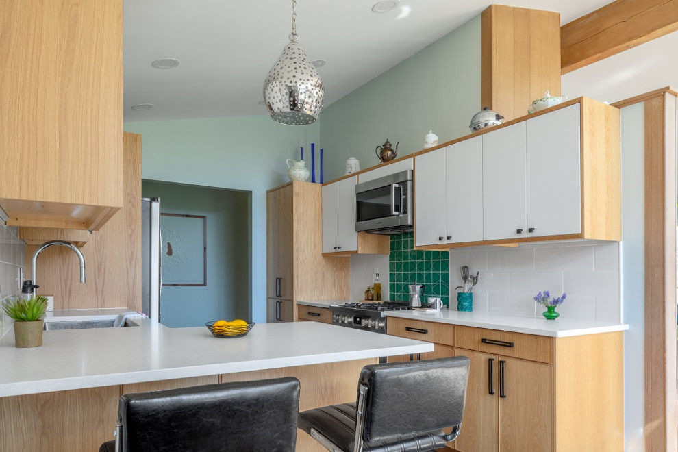 This is an example of a small midcentury galley kitchen in Columbus with a submerged sink, flat-panel cabinets, light wood cabinets, engineered stone countertops, white splashback, ceramic splashback, stainless steel appliances, laminate floors, no island, grey floors and white worktops.