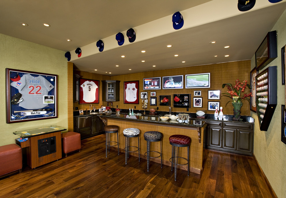 This is an example of a mediterranean basement in Phoenix with green walls, dark hardwood floors and a home bar.