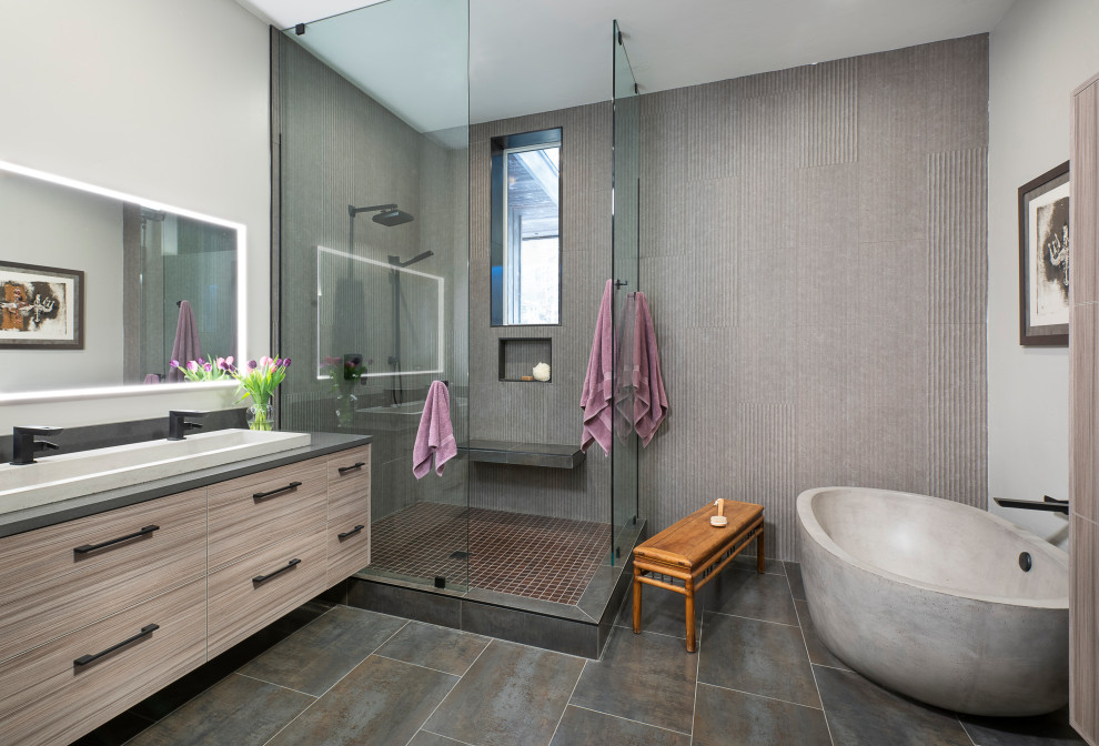 This is an example of a mid-sized contemporary master bathroom in Other with flat-panel cabinets, a freestanding tub, a corner shower, gray tile, ceramic tile, ceramic floors, a trough sink, concrete benchtops, an open shower, grey benchtops, beige cabinets, white walls, grey floor, a niche, a shower seat, a double vanity and a floating vanity.