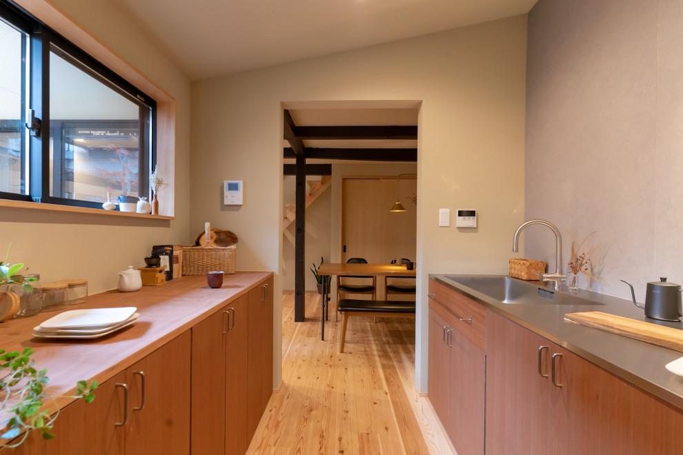 Photo of a world-inspired single-wall enclosed kitchen in Kyoto with a submerged sink, beaded cabinets, brown cabinets, stainless steel worktops, grey splashback, stainless steel appliances, light hardwood flooring, beige floors, brown worktops and a wallpapered ceiling.