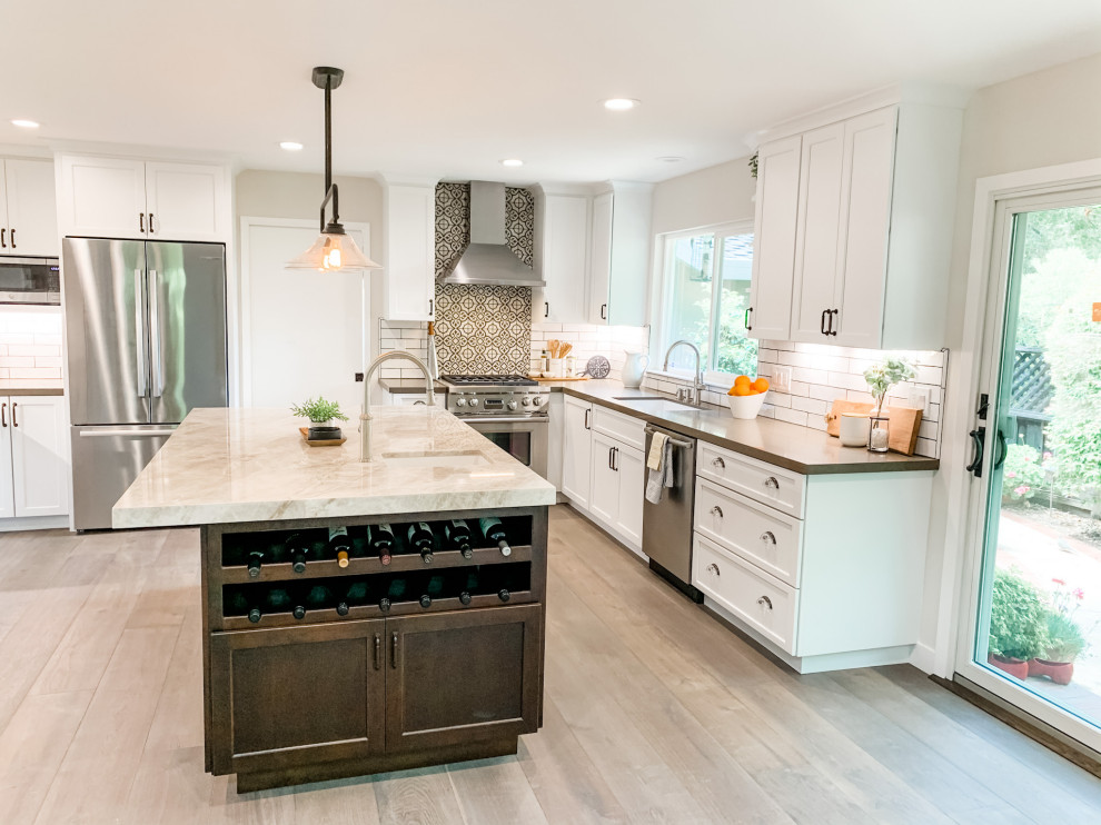 Inspiration for a large country u-shaped open plan kitchen in San Francisco with an undermount sink, shaker cabinets, white cabinets, quartz benchtops, white splashback, porcelain splashback, stainless steel appliances, medium hardwood floors, with island, grey floor and beige benchtop.