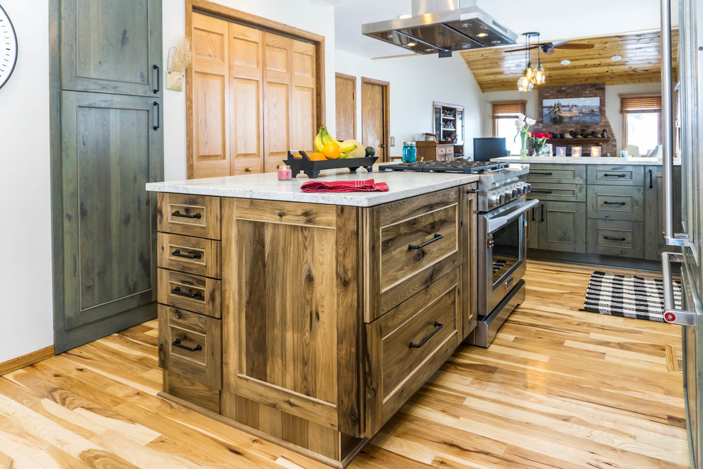 Open concept kitchen - large rustic light wood floor and brown floor open concept kitchen idea with beaded inset cabinets, distressed cabinets, granite countertops, an island and white countertops