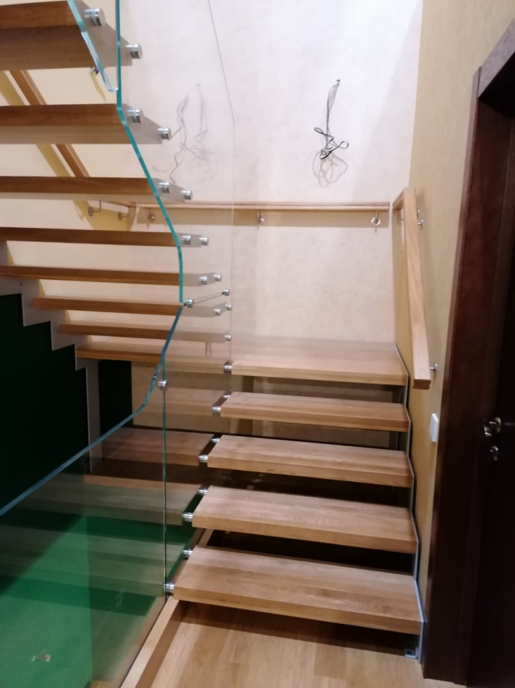 Aménagement d'un escalier contemporain en U de taille moyenne avec des marches en bois, un garde-corps en verre et du papier peint.
