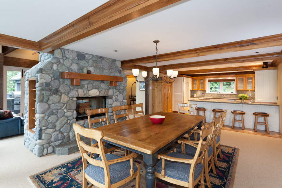This is an example of a large country kitchen/dining combo in Vancouver with beige walls, carpet, a two-sided fireplace and a stone fireplace surround.