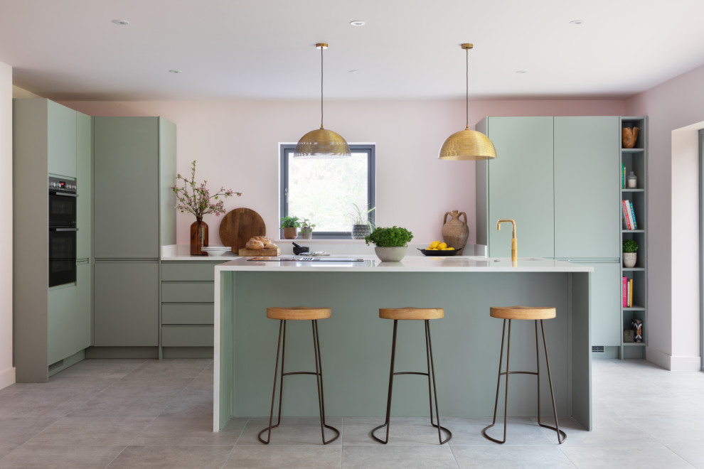 This is an example of a large contemporary u-shaped kitchen/diner in Oxfordshire with a built-in sink, flat-panel cabinets, green cabinets, quartz worktops, multi-coloured splashback, engineered quartz splashback, integrated appliances, ceramic flooring, an island, grey floors, multicoloured worktops, all types of ceiling and feature lighting.