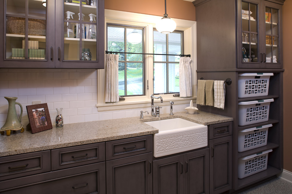 This is an example of a mid-sized traditional galley utility room in Minneapolis with a farmhouse sink, glass-front cabinets, granite benchtops and beige benchtop.