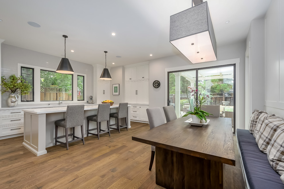 Photo of a large contemporary l-shaped eat-in kitchen in San Francisco with brown floor, an undermount sink, solid surface benchtops, medium hardwood floors, shaker cabinets, white cabinets, panelled appliances and with island.