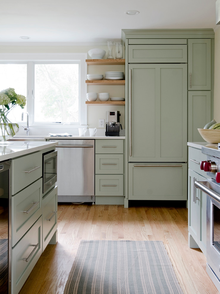 Example of a classic medium tone wood floor kitchen design in Portland Maine with a farmhouse sink, shaker cabinets, green cabinets, paneled appliances and an island