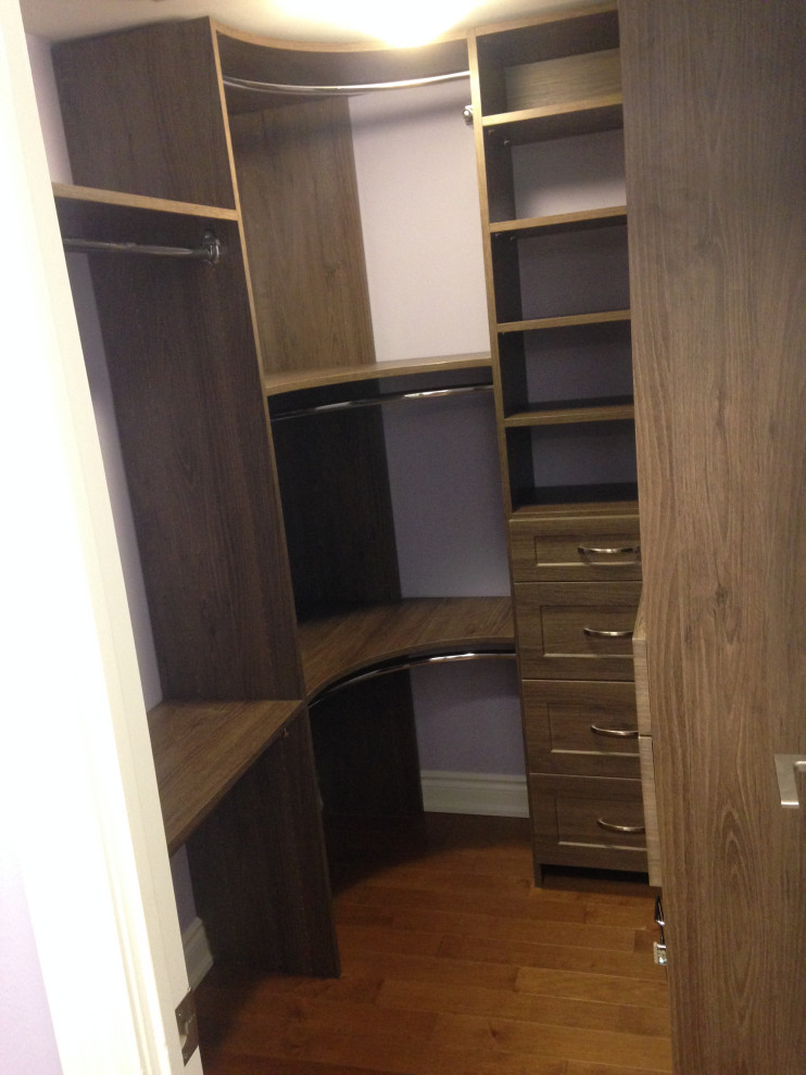 This is an example of a small contemporary gender-neutral walk-in wardrobe in Toronto with shaker cabinets, medium wood cabinets, medium hardwood floors and brown floor.