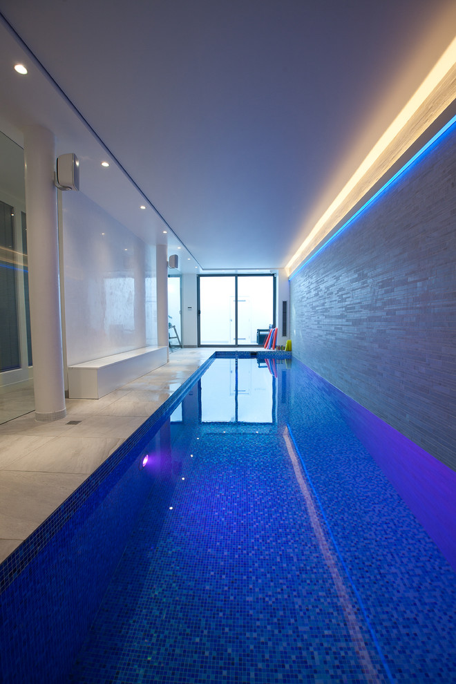 Design ideas for a large contemporary indoor custom-shaped pool in London with a pool house and tile.