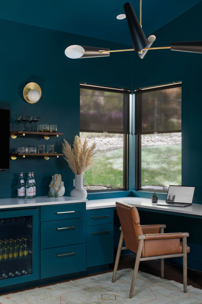 Diseño de despacho moderno de tamaño medio con paredes azules, suelo de madera oscura, escritorio empotrado y suelo marrón