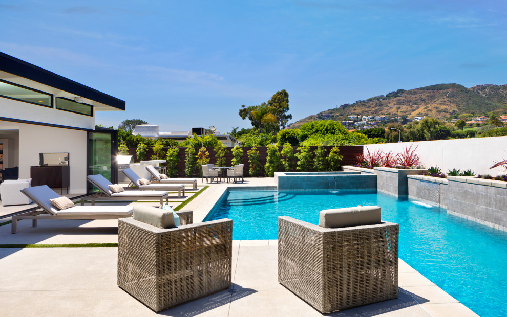 Modelo de piscinas y jacuzzis alargados contemporáneos grandes a medida en patio trasero con adoquines de hormigón