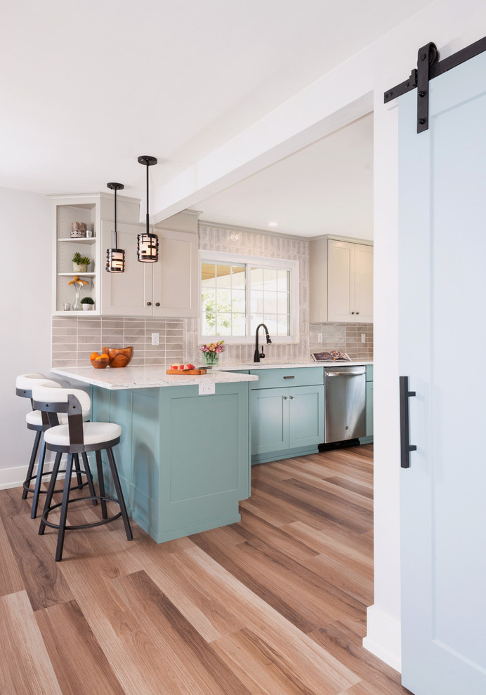 Inspiration for a transitional u-shaped medium tone wood floor and brown floor enclosed kitchen remodel with an undermount sink, shaker cabinets, turquoise cabinets, quartzite countertops, gray backsplash, porcelain backsplash, stainless steel appliances, a peninsula and white countertops