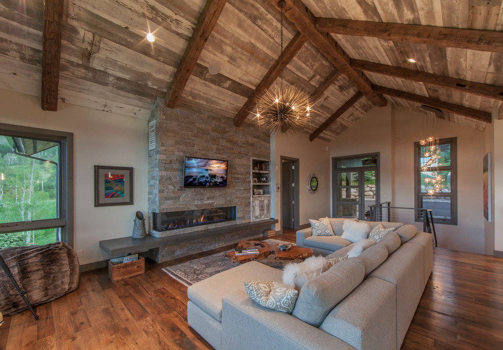 Design ideas for a mid-sized country living room in Denver with grey walls, medium hardwood floors, a ribbon fireplace, a stone fireplace surround and a wall-mounted tv.
