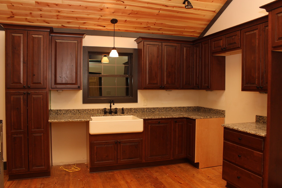 Photo of a mid-sized country l-shaped eat-in kitchen in Atlanta with a farmhouse sink, raised-panel cabinets, medium wood cabinets, granite benchtops and light hardwood floors.