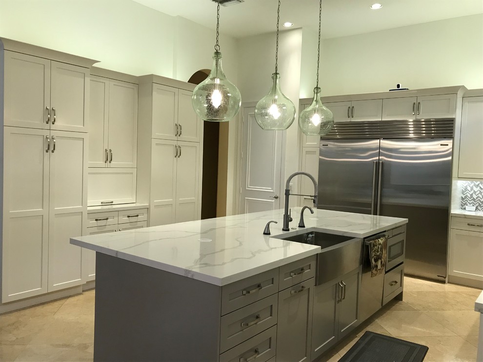 Large transitional kitchen in Miami with a farmhouse sink, shaker cabinets, white cabinets, quartz benchtops, grey splashback, glass tile splashback, stainless steel appliances, with island and multi-coloured benchtop.