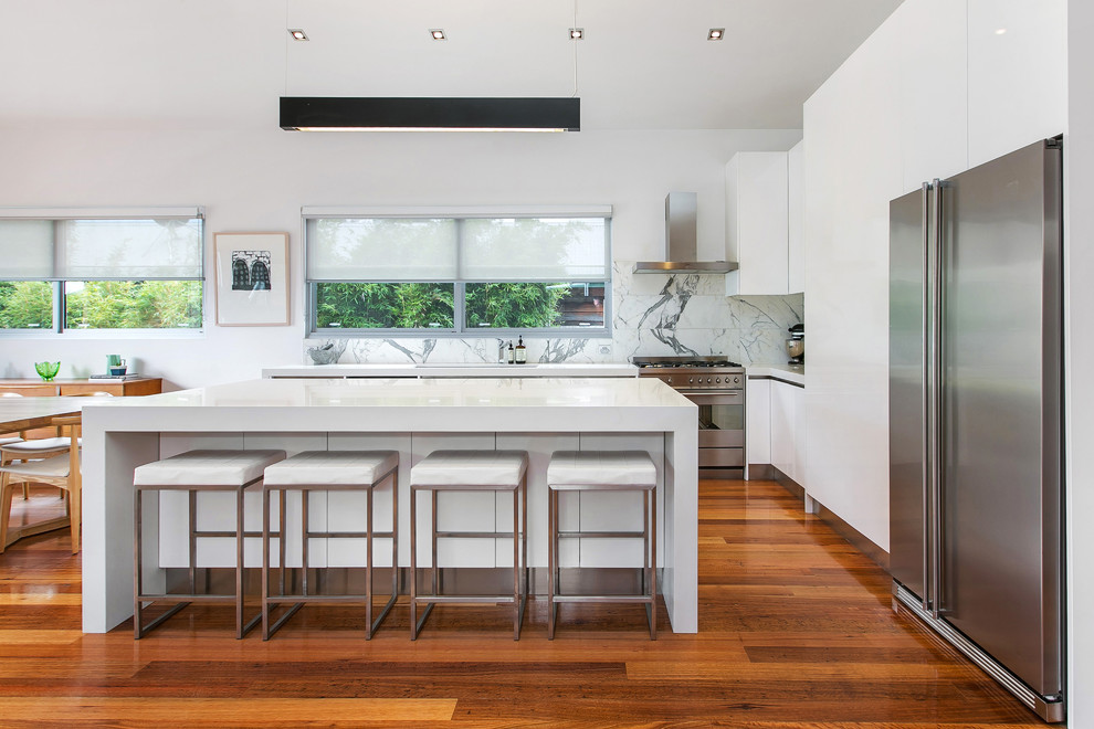 Inspiration for a mid-sized contemporary l-shaped eat-in kitchen in Melbourne with with island, an undermount sink, white cabinets, granite benchtops, white splashback, ceramic splashback, stainless steel appliances and medium hardwood floors.