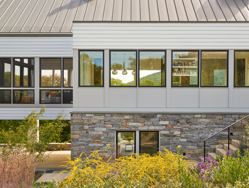Photo of a large contemporary two-storey white exterior in DC Metro with stone veneer and a gable roof.