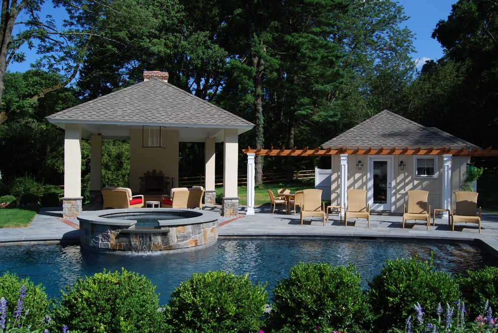 Large traditional backyard custom-shaped pool in Philadelphia with a pool house and natural stone pavers.