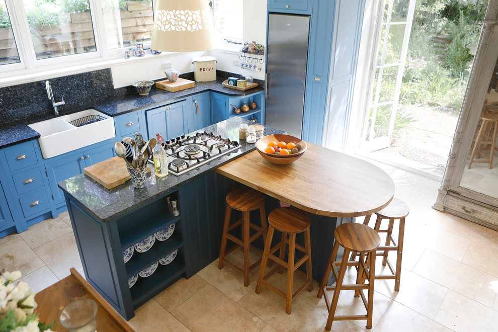 Design ideas for a mid-sized country eat-in kitchen in Kent with raised-panel cabinets, blue cabinets, wood benchtops and with island.