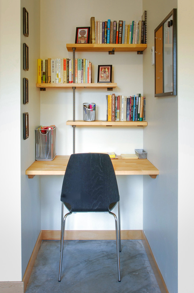 Small trendy open concept and built-in desk concrete floor home office photo with white walls