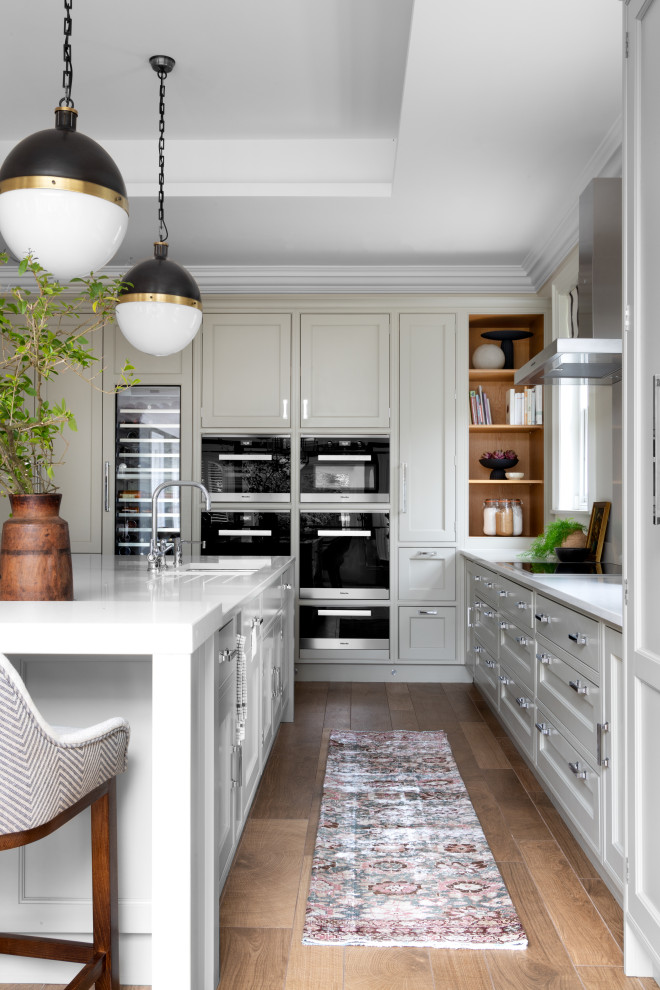 Exempel på ett stort klassiskt vit vitt kök, med skåp i shakerstil, grå skåp, bänkskiva i kvarts, vitt stänkskydd, rostfria vitvaror, klinkergolv i porslin, en köksö och brunt golv