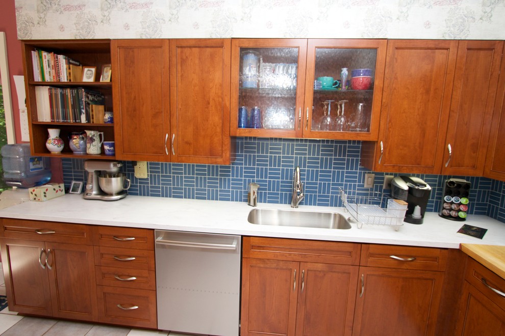 Example of a transitional l-shaped ceramic tile open concept kitchen design in Baltimore with an undermount sink, recessed-panel cabinets, medium tone wood cabinets, solid surface countertops, blue backsplash, ceramic backsplash, stainless steel appliances and an island