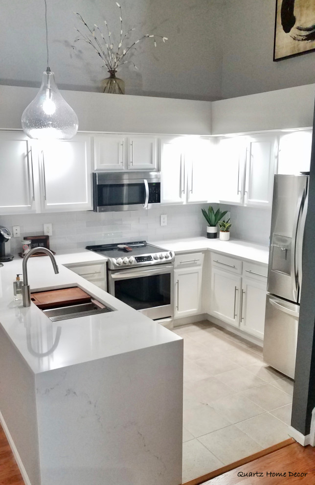 This is an example of a small modern u-shaped eat-in kitchen in Denver with a double-bowl sink, white cabinets, quartzite benchtops, grey splashback, glass tile splashback, stainless steel appliances, ceramic floors, beige floor, white benchtop and vaulted.