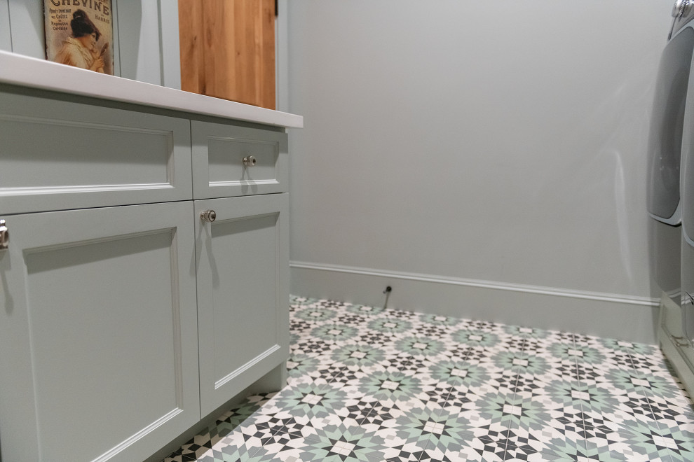 Large country u-shaped dedicated laundry room in Houston with a drop-in sink, recessed-panel cabinets, grey cabinets, grey splashback, shiplap splashback, grey walls, porcelain floors, a side-by-side washer and dryer, multi-coloured floor and white benchtop.