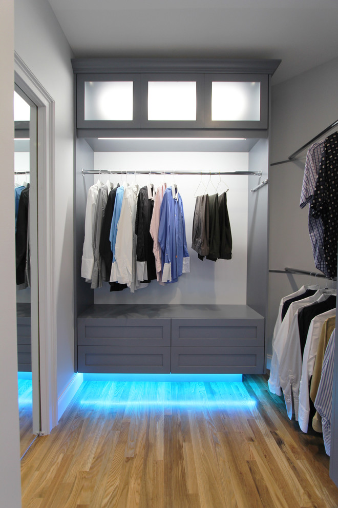 This is an example of a mid-sized contemporary gender-neutral dressing room in Atlanta with shaker cabinets, grey cabinets and light hardwood floors.