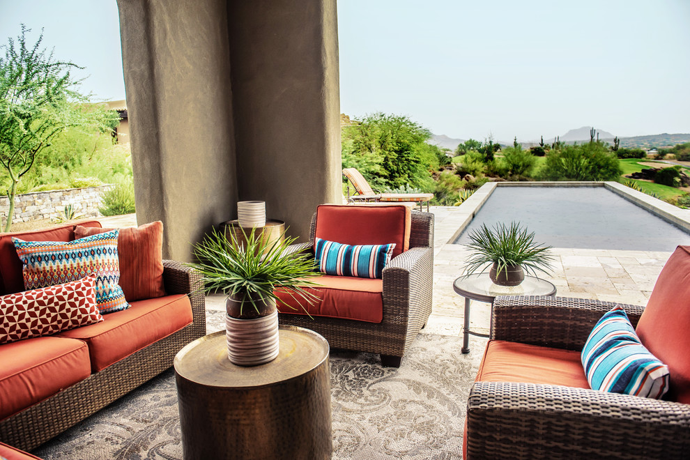 Example of a large transitional backyard stone patio design in Phoenix with a roof extension