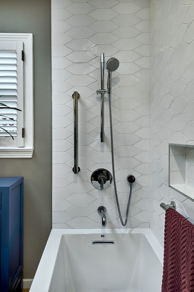 Inspiration for a small transitional 3/4 bathroom in San Francisco with flat-panel cabinets, blue cabinets, a corner tub, a shower/bathtub combo, a one-piece toilet, white tile, ceramic tile, grey walls, light hardwood floors, a pedestal sink, yellow floor, an open shower and white benchtops.