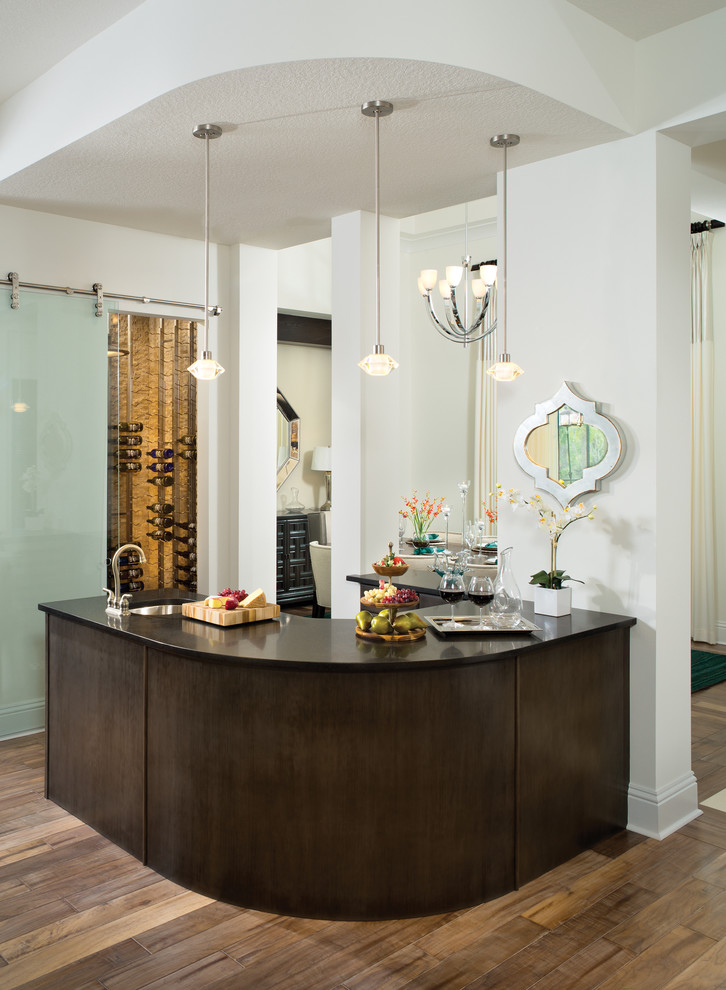 Photo of a mediterranean u-shaped wet bar in Tampa with dark hardwood floors, an undermount sink, flat-panel cabinets and dark wood cabinets.