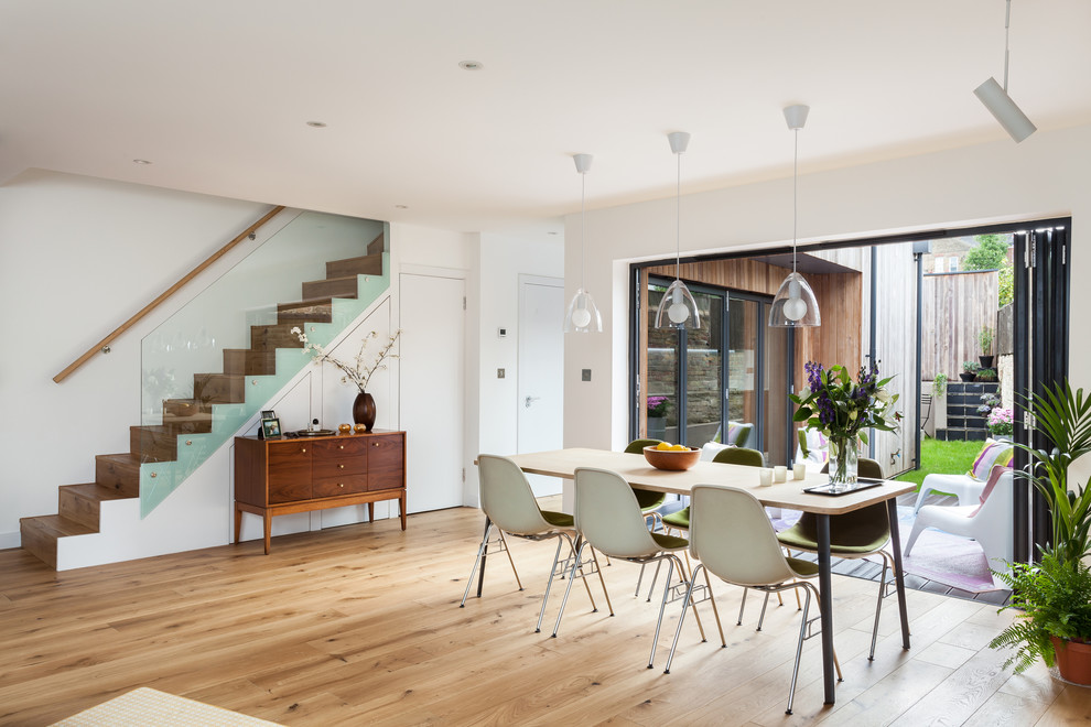 Photo of a mid-sized contemporary dining room in London with white walls and light hardwood floors.