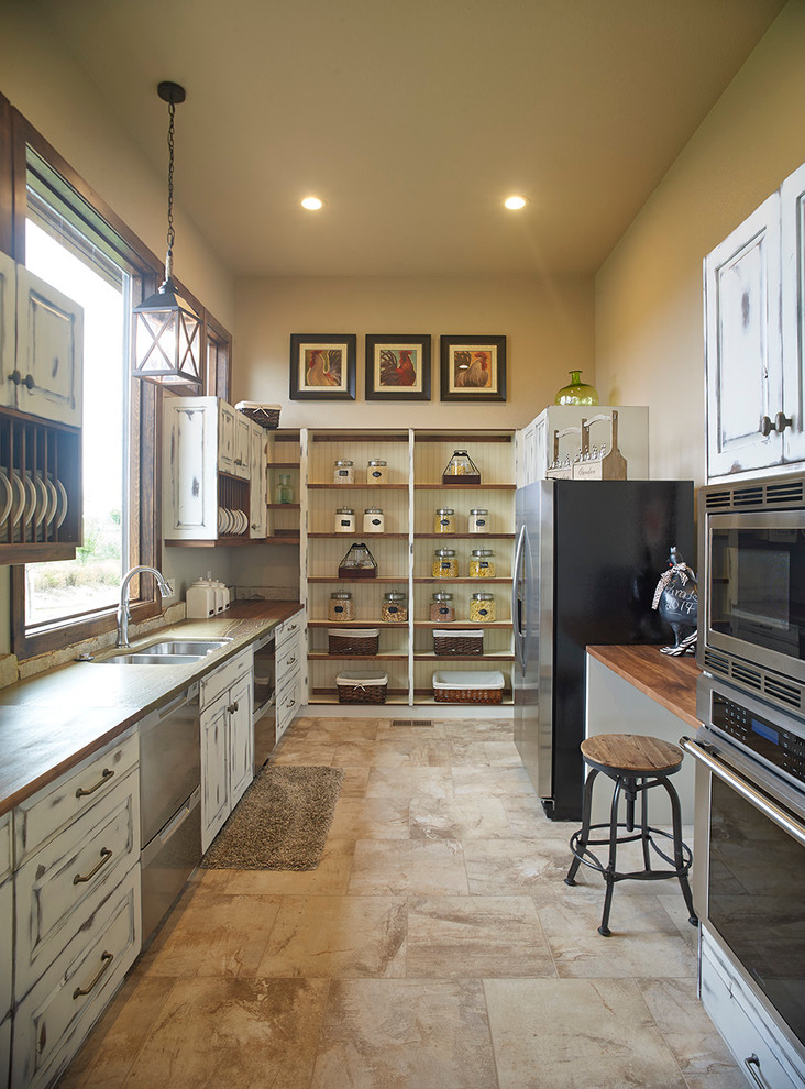 Inspiration for a large country galley kitchen in Denver with a double-bowl sink, raised-panel cabinets, distressed cabinets, wood benchtops, stainless steel appliances, ceramic floors and no island.