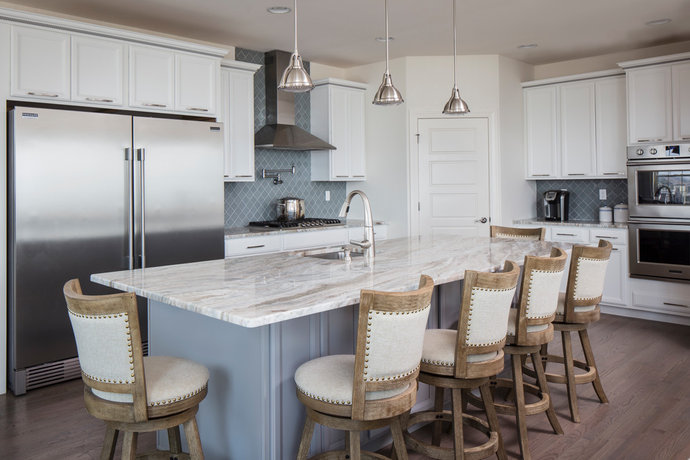 Traditional kitchen in New York with an undermount sink, recessed-panel cabinets, white cabinets, grey splashback, stainless steel appliances, medium hardwood floors and with island.