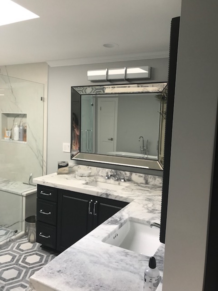 Mid-sized transitional master bathroom in New York with raised-panel cabinets, black cabinets, a corner shower, white tile, stone slab, grey walls, marble floors, an undermount sink, marble benchtops, multi-coloured floor and a hinged shower door.