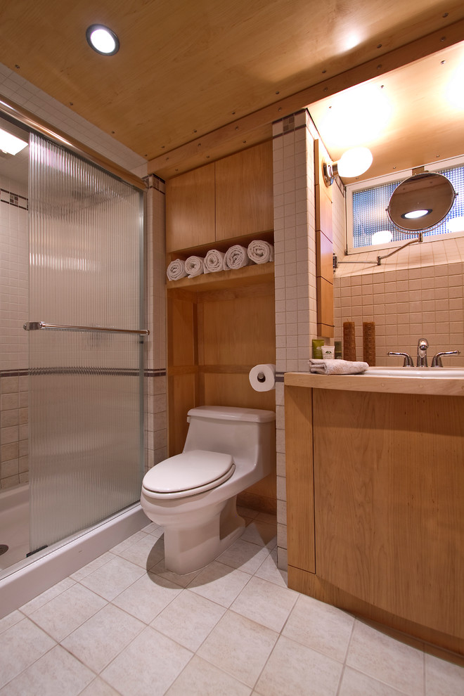 Inspiration for a small contemporary 3/4 bathroom in Philadelphia with a drop-in sink, flat-panel cabinets, an alcove shower, a one-piece toilet, beige tile, ceramic tile, white walls, ceramic floors and medium wood cabinets.
