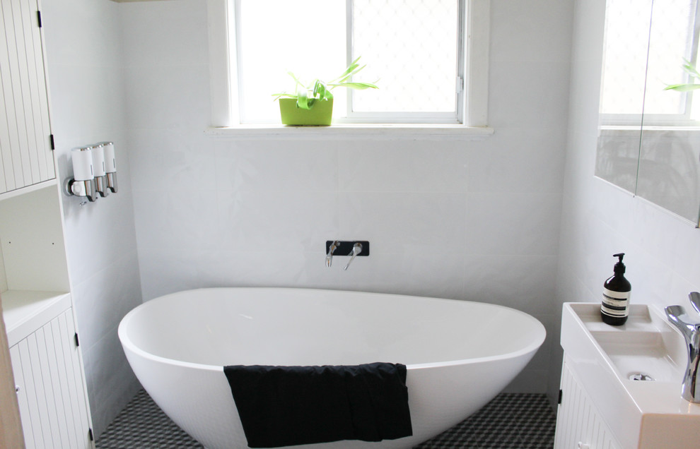 Photo of a small kids wet room bathroom in Perth with shaker cabinets, white cabinets, a freestanding tub, a one-piece toilet, white tile, ceramic tile, white walls, mosaic tile floors, an integrated sink, solid surface benchtops, multi-coloured floor and white benchtops.