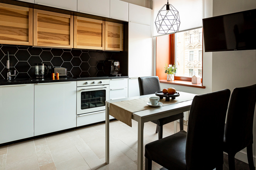 Mid-sized contemporary single-wall eat-in kitchen in Saint Petersburg with a drop-in sink, recessed-panel cabinets, medium wood cabinets, marble benchtops, black splashback, white appliances, porcelain floors, beige floor, black benchtop and shiplap splashback.