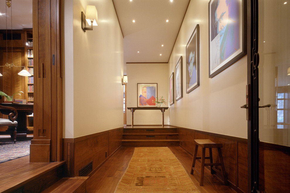 Photo of a traditional hallway in New York with beige walls and dark hardwood floors.
