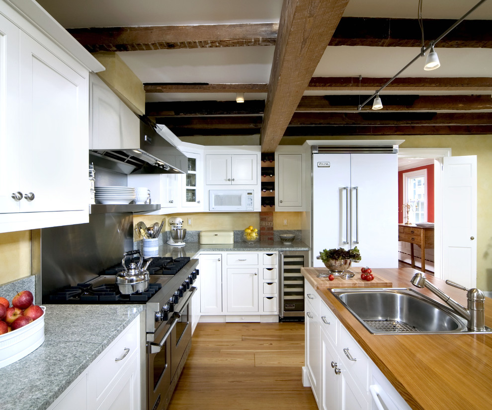 Traditional kitchen in DC Metro with white appliances, wood benchtops, a drop-in sink, beaded inset cabinets and white cabinets.