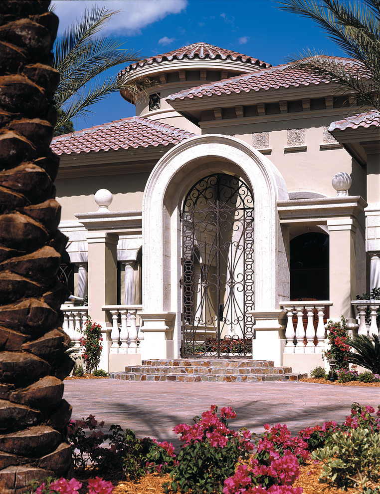 Photo of an expansive mediterranean two-storey stucco beige exterior in Miami.