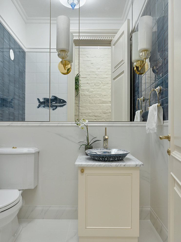 This is an example of a traditional powder room in Moscow with beige cabinets, blue tile, white tile, porcelain tile, porcelain floors, marble benchtops, recessed-panel cabinets, a two-piece toilet, white walls, a vessel sink and white floor.