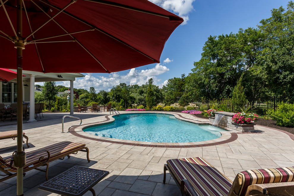 Photo of a traditional kidney-shaped pool in Providence with natural stone pavers.