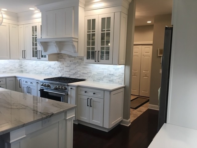 Large transitional u-shaped dark wood floor and brown floor eat-in kitchen photo with an undermount sink, recessed-panel cabinets, white cabinets, marble countertops, white backsplash, stone tile backsplash, stainless steel appliances, an island and white countertops