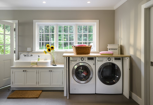 Front-load washer and dryer fitted beneath a countertop beside a sink base, illustrating the difference between cut-out openings and overall appliance face size