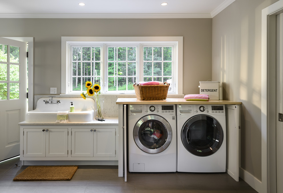 This is an example of a mid-sized country utility room in New York with shaker cabinets, white cabinets, marble benchtops, ceramic floors, a side-by-side washer and dryer, beige benchtop, a drop-in sink and grey walls.