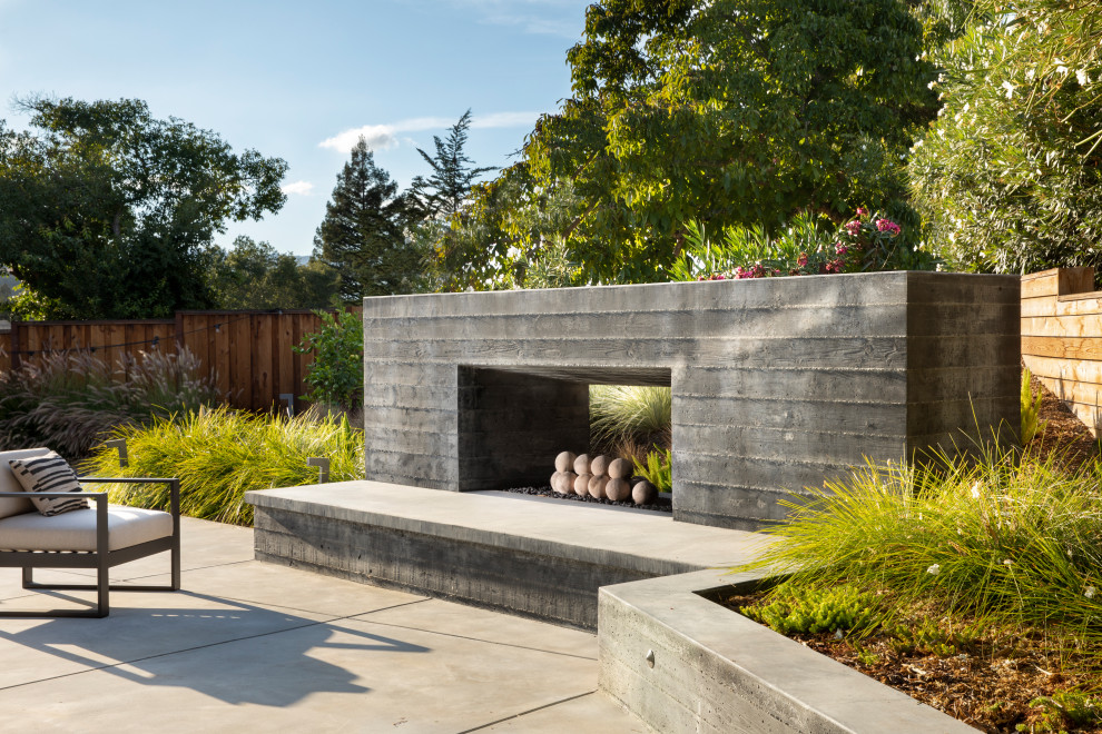 This is an example of a medium sized scandinavian back patio in San Francisco with a fireplace and concrete slabs.