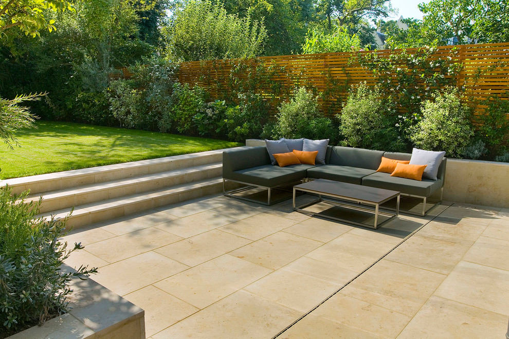 Design ideas for a mid-sized contemporary backyard patio in London with natural stone pavers and no cover.